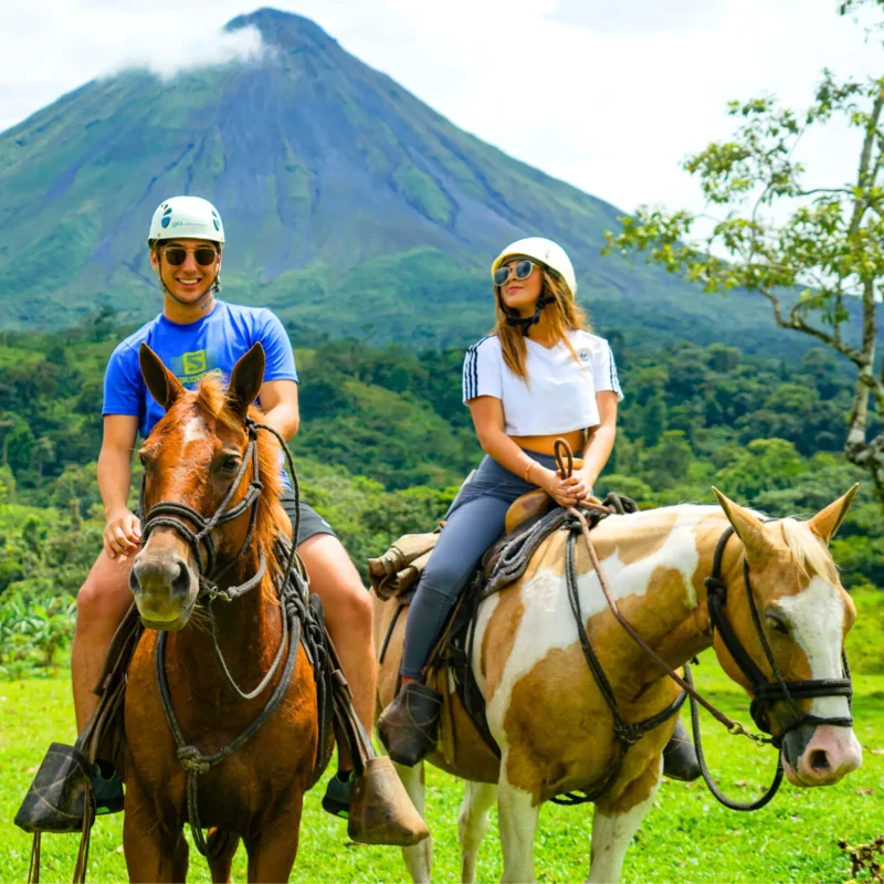 Couple horseback riding with scenic Arenal Volcano in the background during a Wave Costa Rica tour