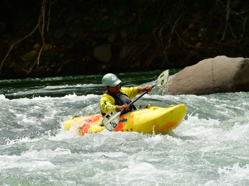 Safety kayaker guiding the group during Arenal rafting on Class III rapids.