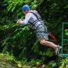 Man jumping from a canyon swing platform in the jungle with safety gear in Costa Rica