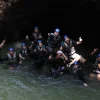 Adventure group resting in a jungle river cave during a canyoning tour in Rainforest Falls, Costa Rica.