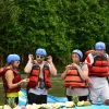 Group of travelers in life jackets enjoying a tropical fruit snack break during a whitewater rafting tour in Arenal, Costa Rica.