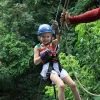 Smiling little girl on a canopy line surrounded by jungle – Wave Rafting La Fortuna tour