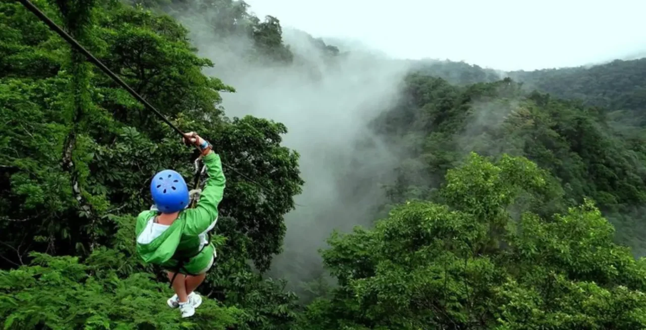Person ziplining through the forest with volcano view in La Fortuna, Costa Rica